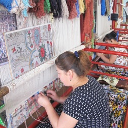 Lady working on an original design on silk carpet made with naturally dyed silk threads.